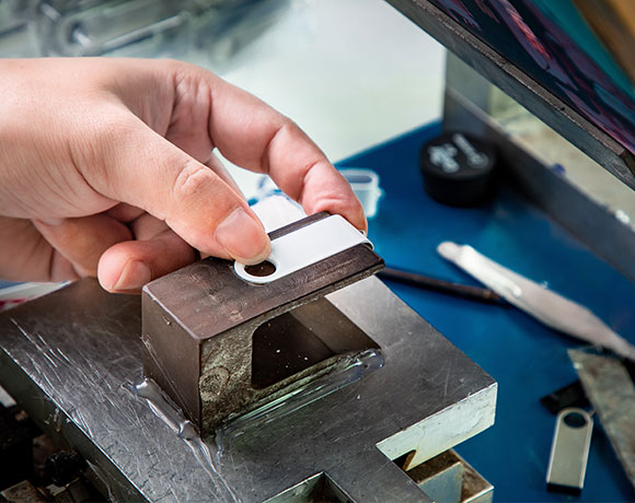 a worker is printing a metal USB flash drives with logo